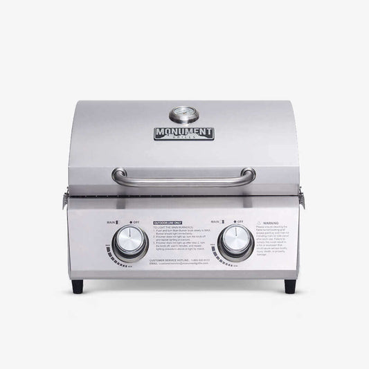 Stainless steel portable tabletop propane gas grill with two burners at an outdoor tailgate