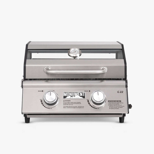 G22 stainless steel portable tabletop propane gas grill with locking lid at a campsite
